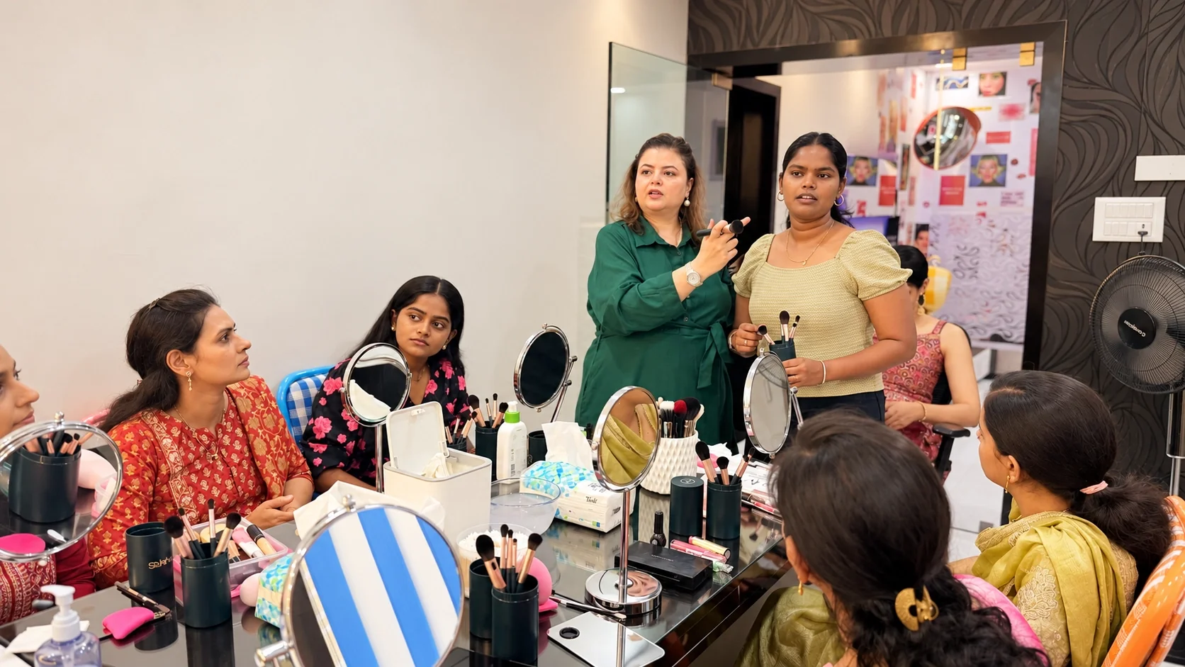 Rekha explaining a technique with a brush to a student while the class watches